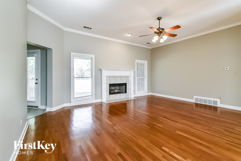 A spacious room with a fireplace and wood flooring.