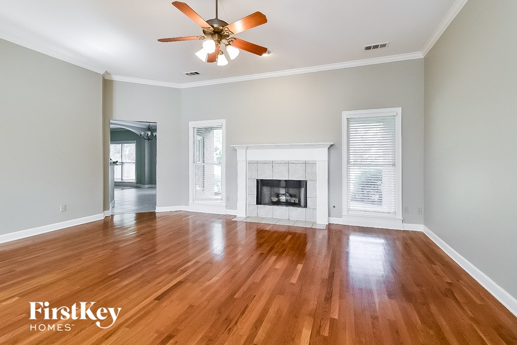 A spacious living room with a fireplace and wood flooring.