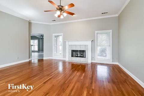 A spacious living room with a fireplace and wood flooring.