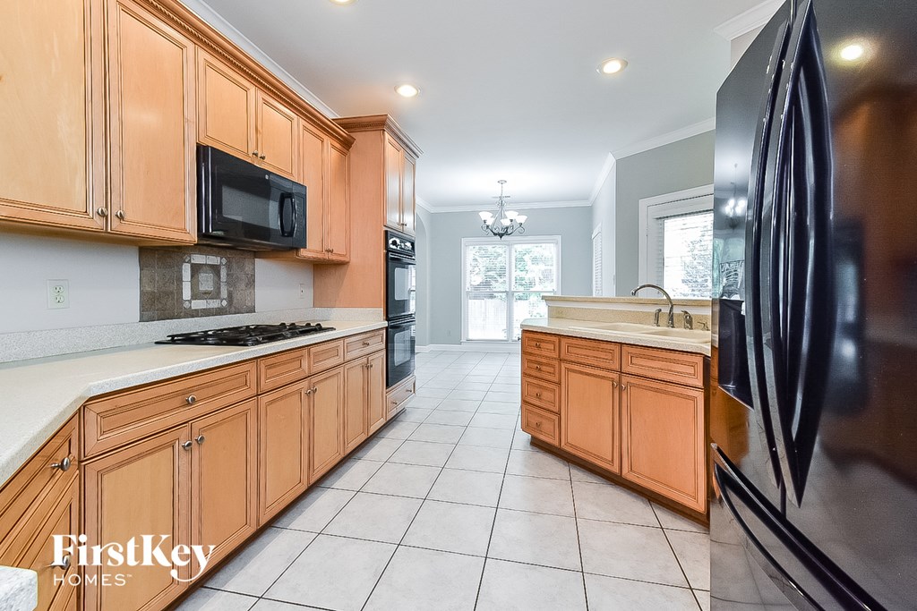 A kitchen with wooden cabinets and a black fridge.