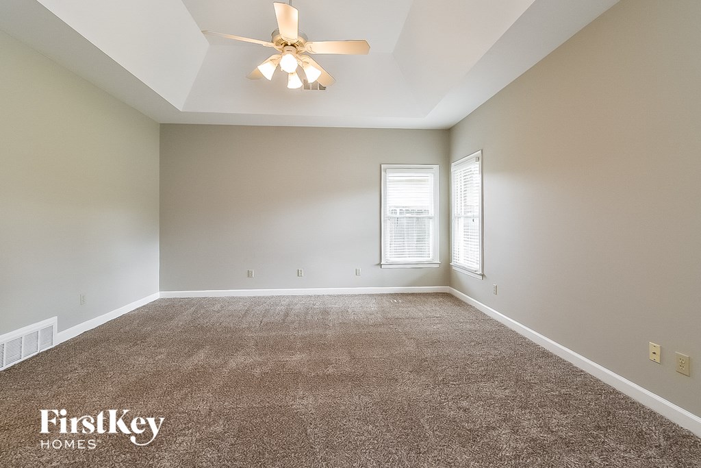 A spacious room with a ceiling fan and carpeted floor.