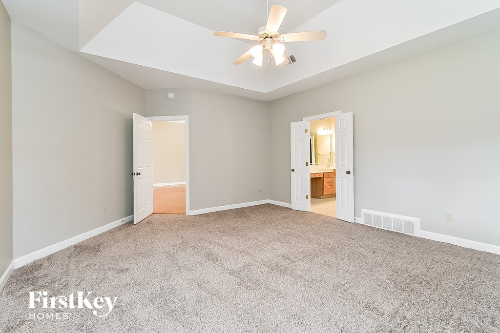 A spacious room with a ceiling fan and two doors.