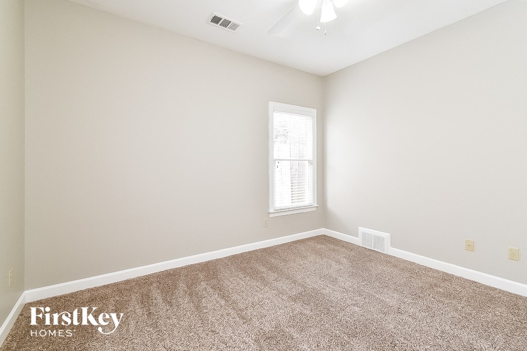A room with a carpeted floor and a window letting in light.