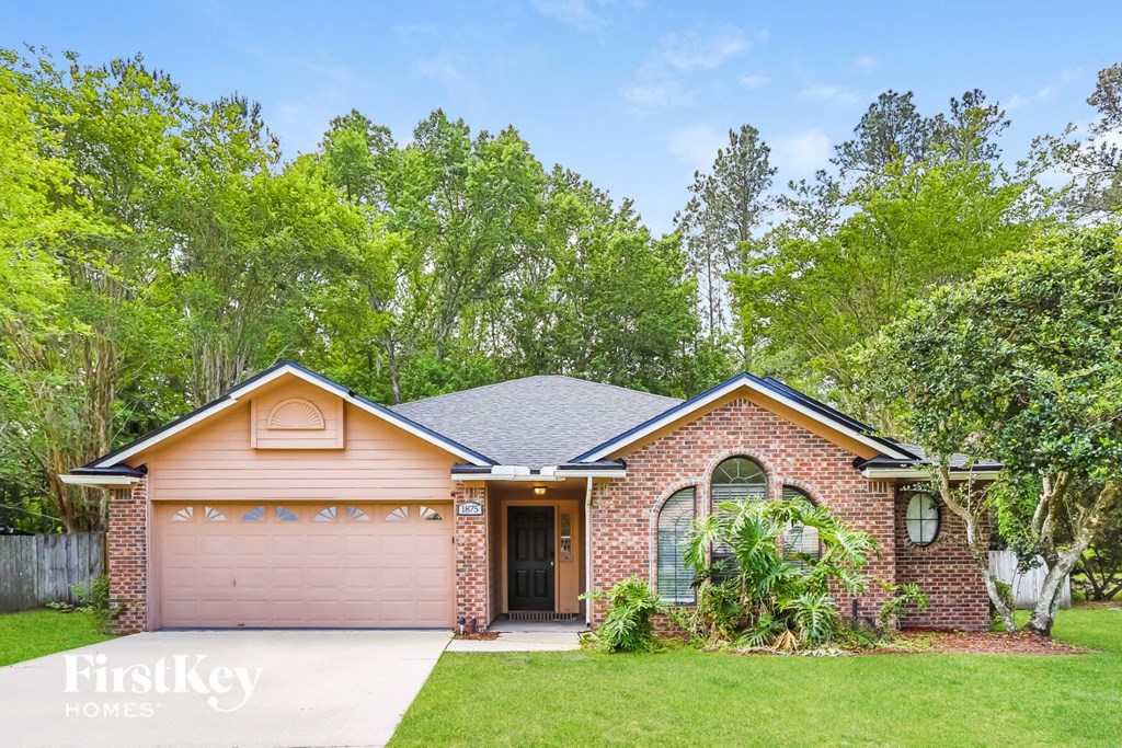 A brick house with a brown garage door is for sale.