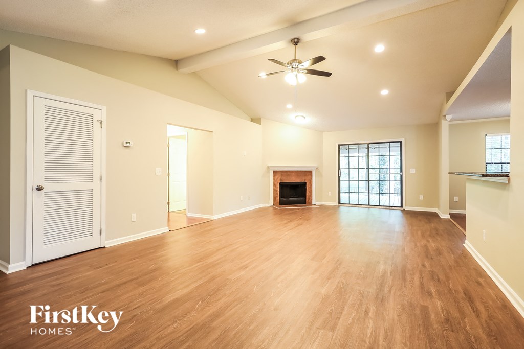 A spacious living room with wood flooring and a fireplace.