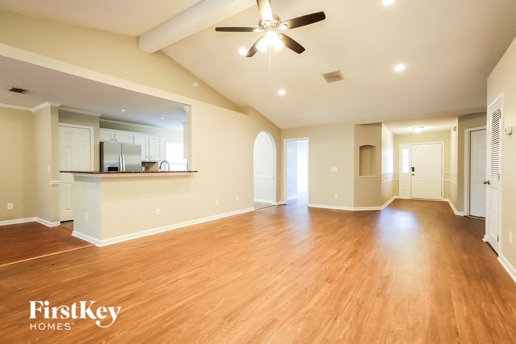 A spacious room with wooden floors and a ceiling fan.