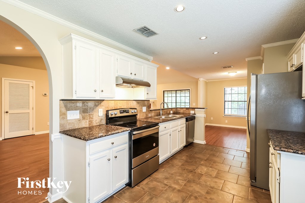 A kitchen with a black refrigerator and white cabinets.