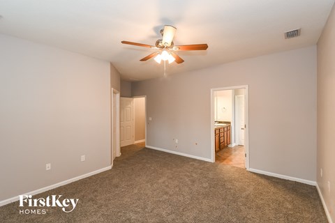 a spacious living room with carpet and a ceiling fan