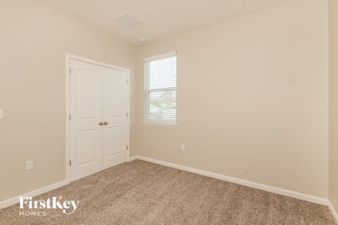 a bedroom with carpet and a door and a window