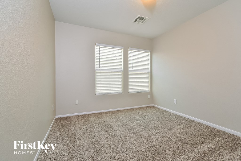 an empty room with carpet and two windows