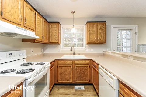 A kitchen with wooden cabinets and a white stove top oven.