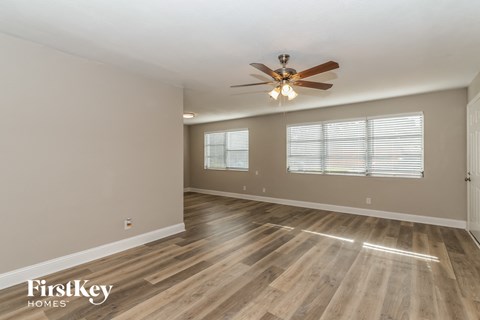A spacious room with a ceiling fan and wooden flooring.