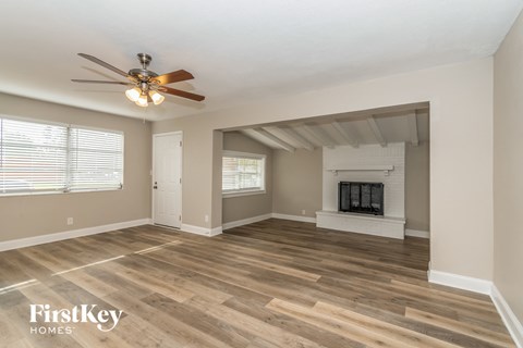 A spacious living room with a fireplace and a ceiling fan.