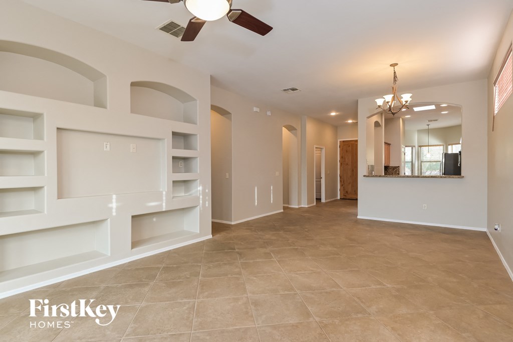 an empty living room with white shelves and a ceiling fan