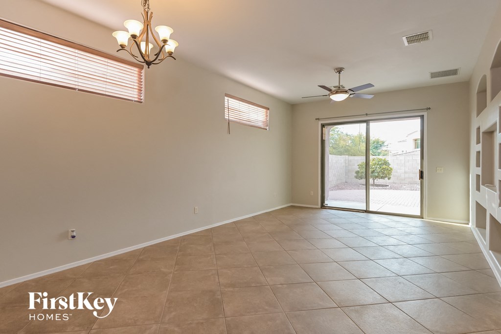 an empty living room with a ceiling fan and a sliding glass door