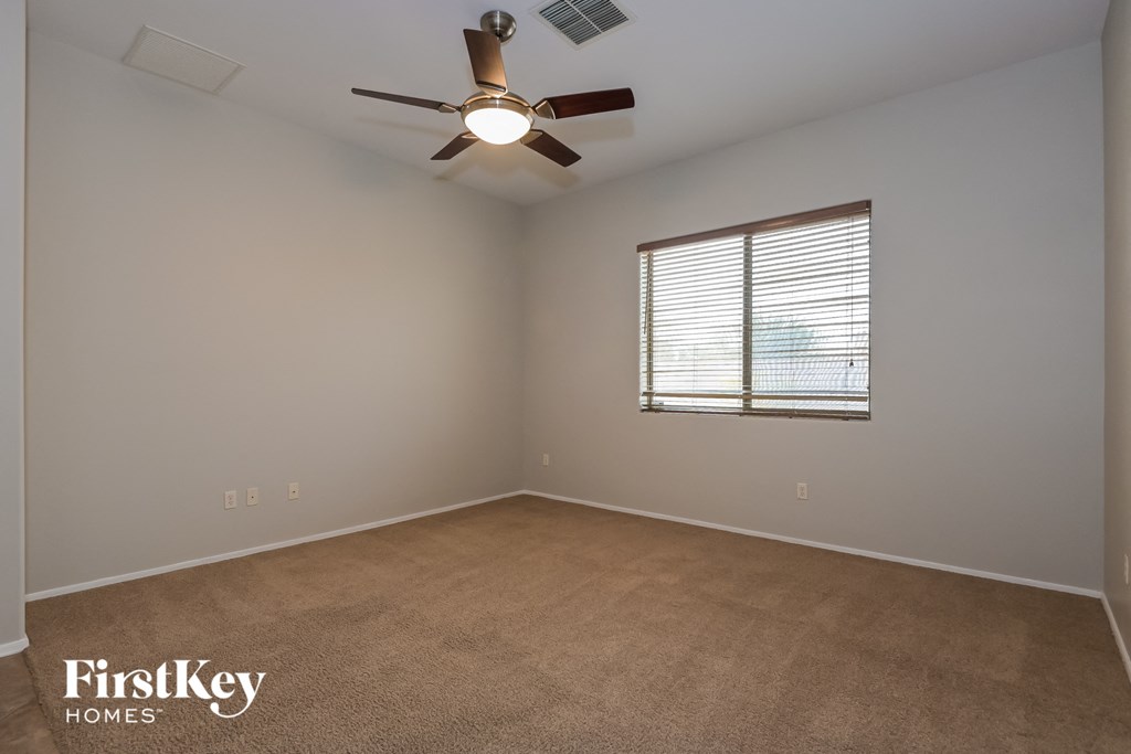 an empty room with a ceiling fan and a window