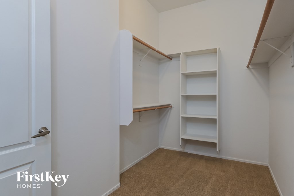 a walk in closet with white shelves and a white door