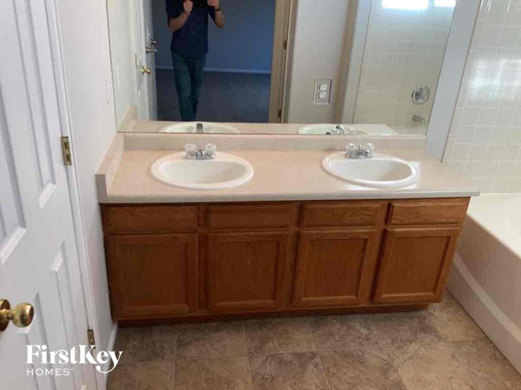 a woman taking a picture of a bathroom vanity with two sinks