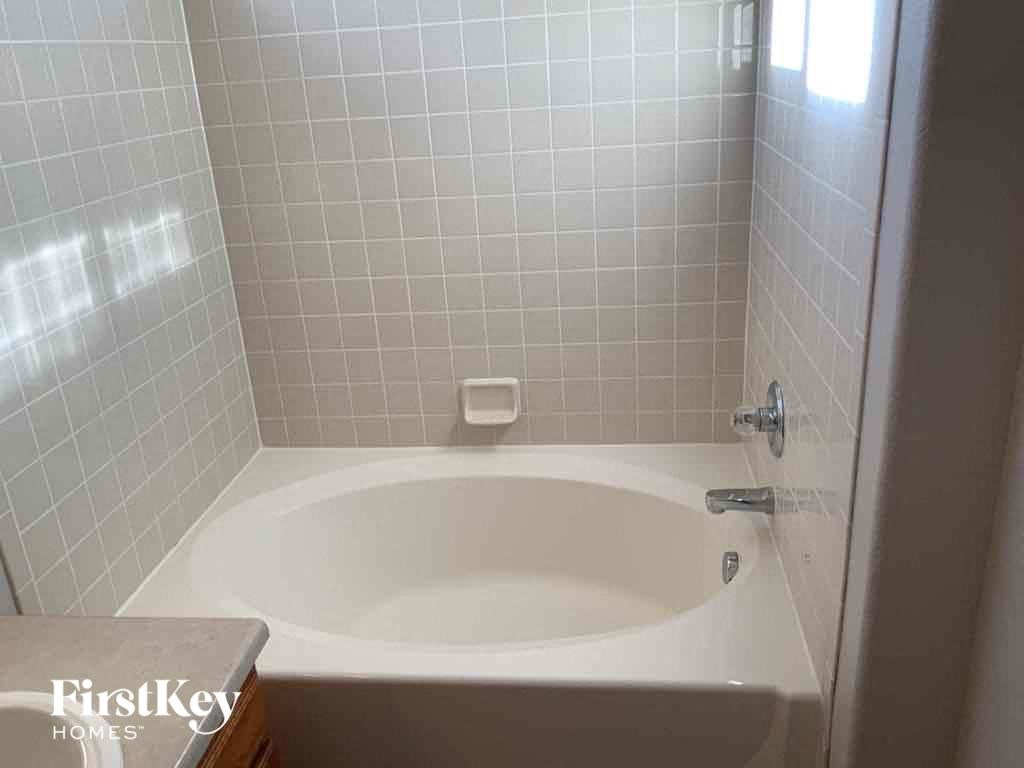 a white bath tub in a white tiled bathroom