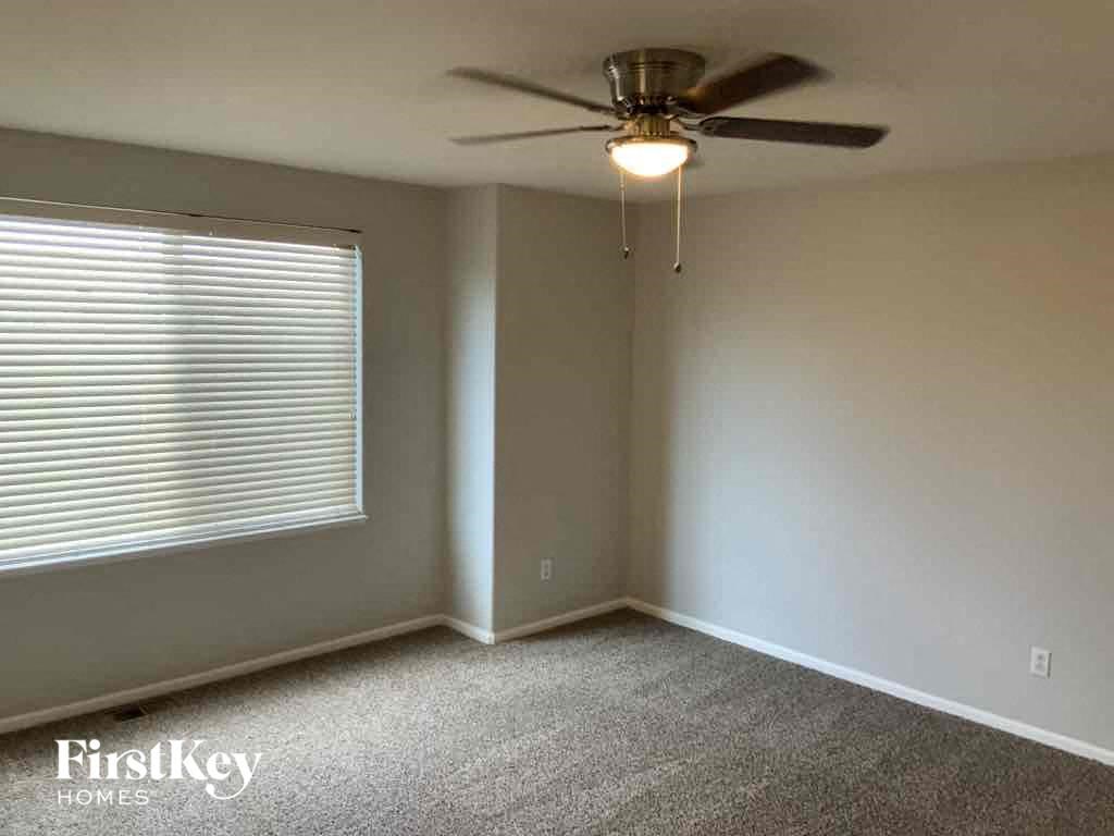 an empty living room with a ceiling fan and a window