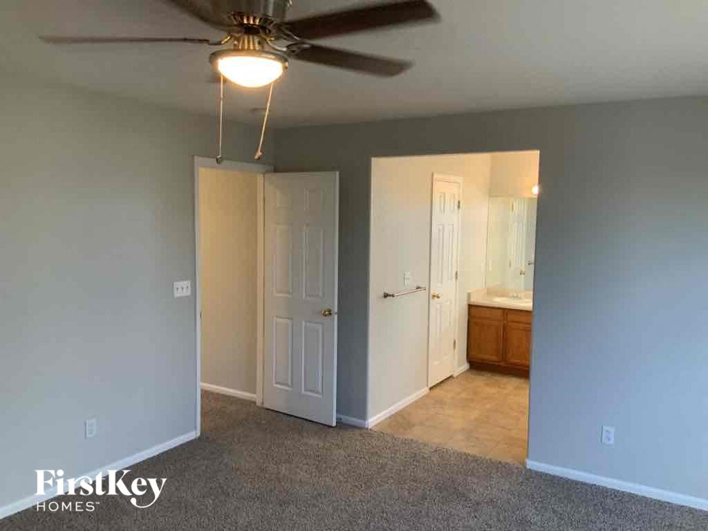an empty living room with a ceiling fan and a door to a bathroom