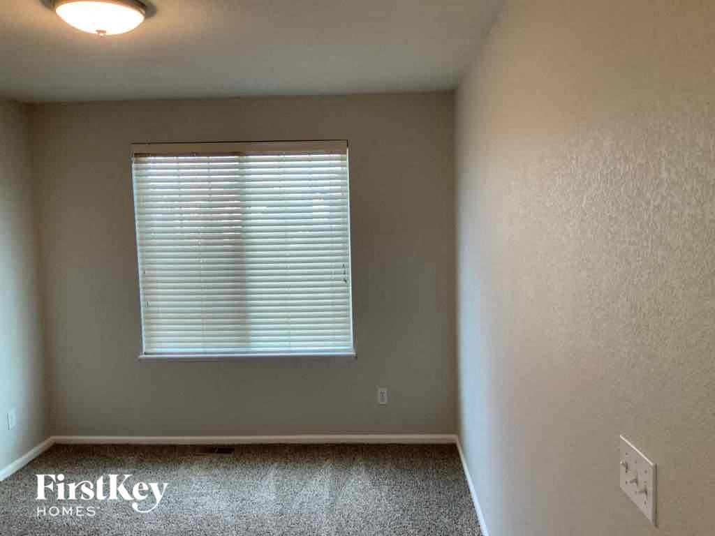 an empty room with a window and a light on the wall