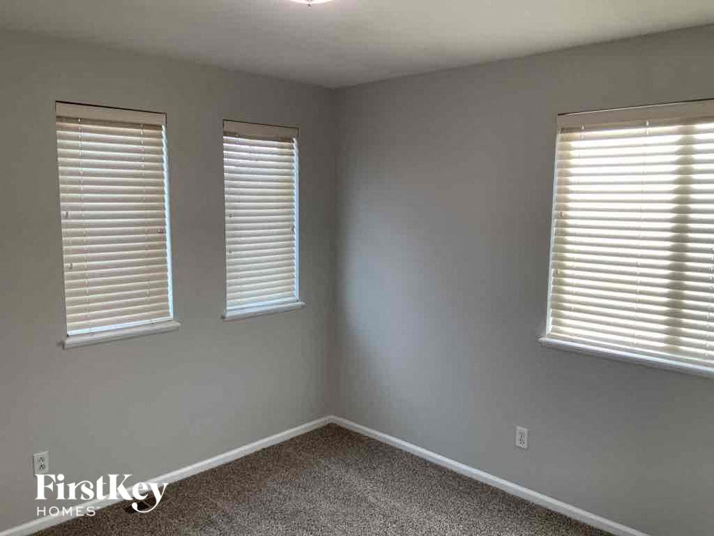 a bedroom with three windows and a carpeted floor