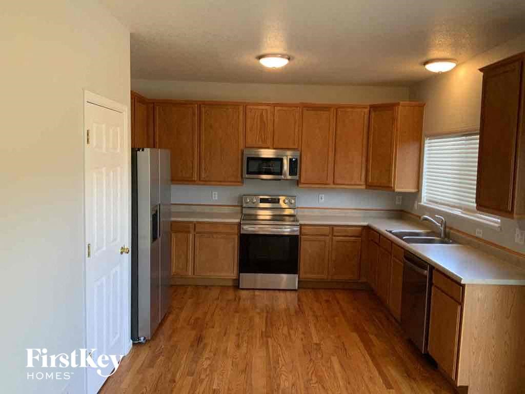 an empty kitchen with wooden cabinets and a refrigerator