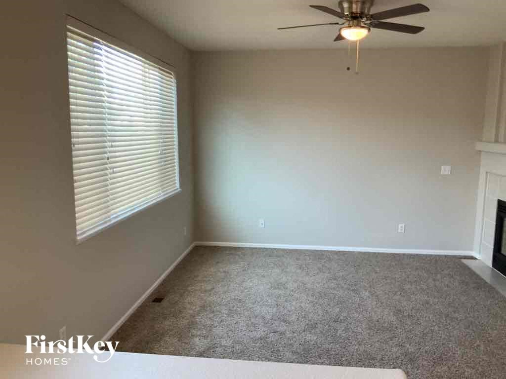 an empty living room with a ceiling fan and a window