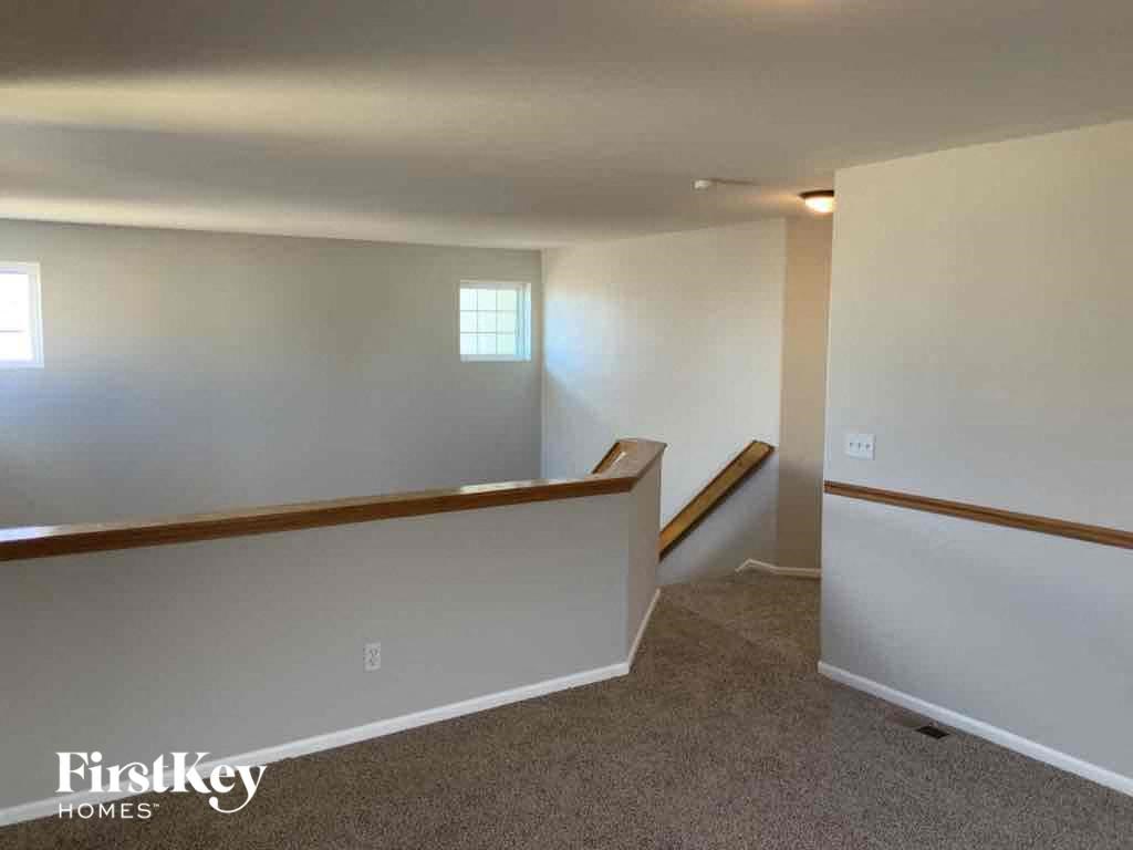 an empty basement with white walls and a carpeted floor and stairs