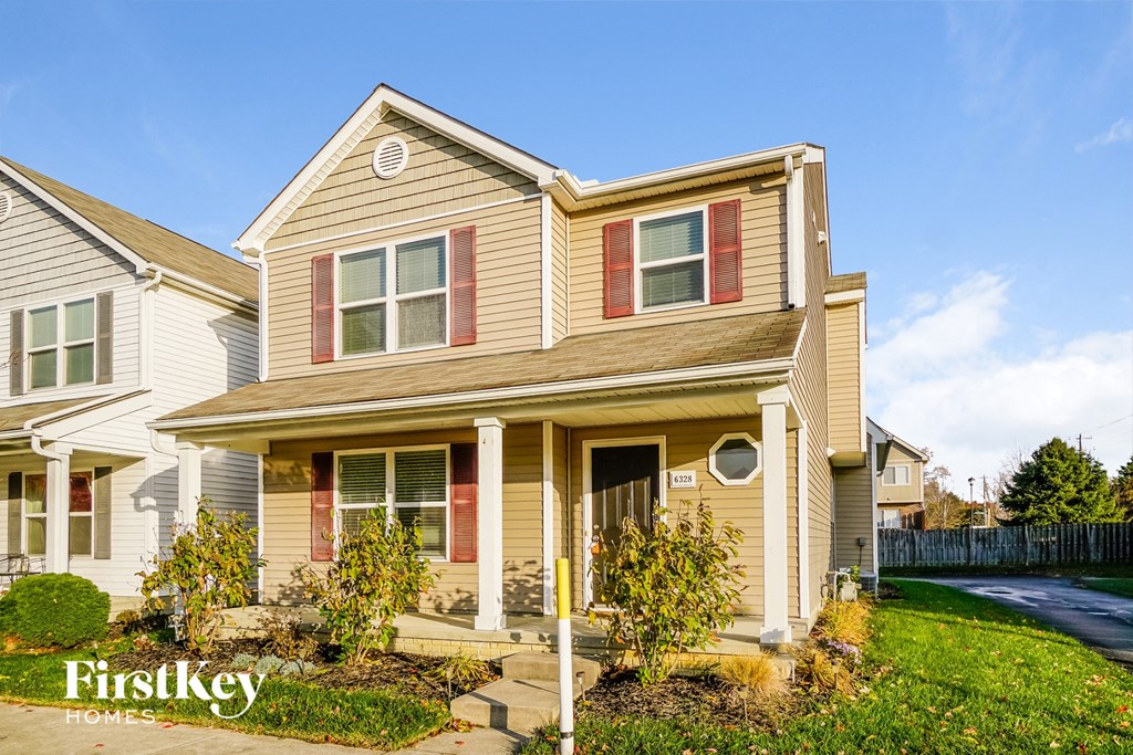 a beige house with red shutters and a lawn