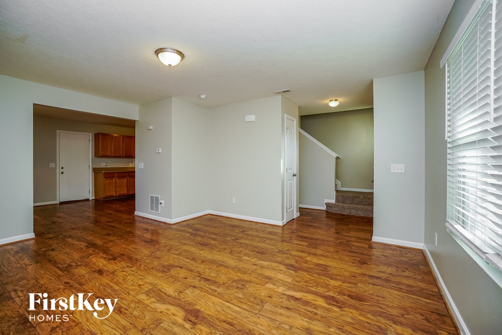 the living room and dining room with wood flooring and white walls