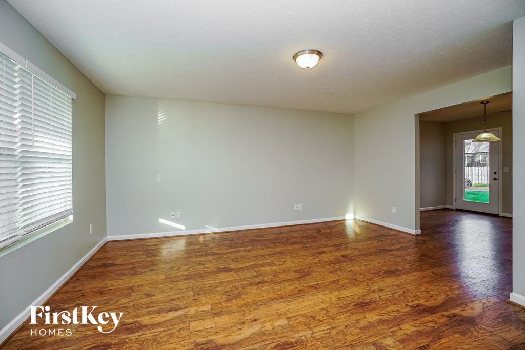 the living room and dining room of an empty house with wood flooring