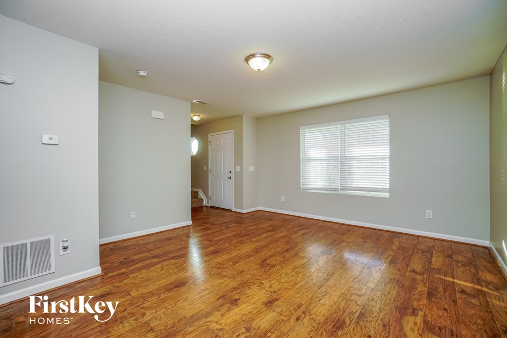 the living room and dining room with hardwood flooring and a window