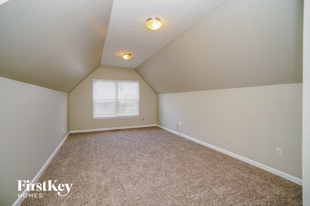 the attic of a house with carpet and a window