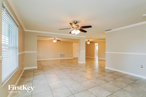 an empty living room with a ceiling fan and tiled floors