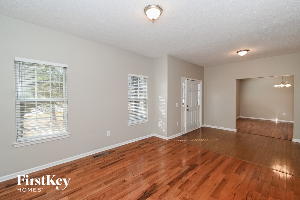 A room with wooden floors and a window with blinds.