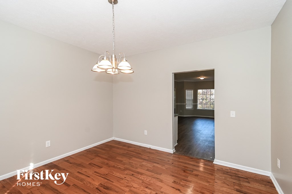 A room with wooden floors and a chandelier hanging from the ceiling.