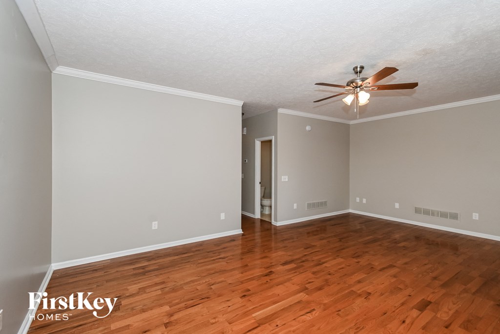 A room with a ceiling fan and wooden floors.