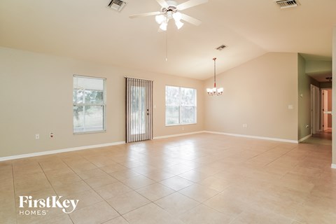 A spacious room with a fan and a chandelier.