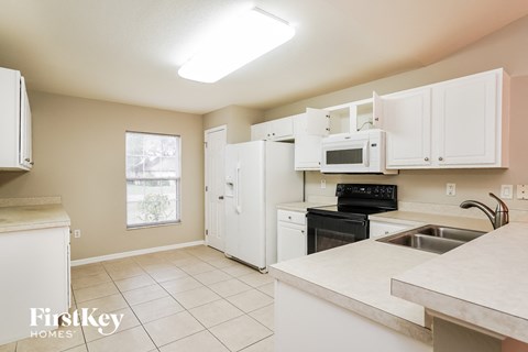 A kitchen with white cabinets and appliances.
