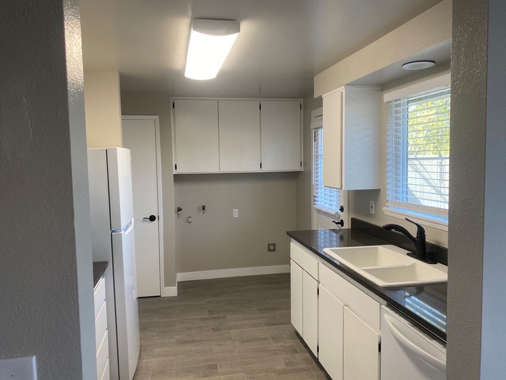 a kitchen with white cabinets and a sink and a refrigerator