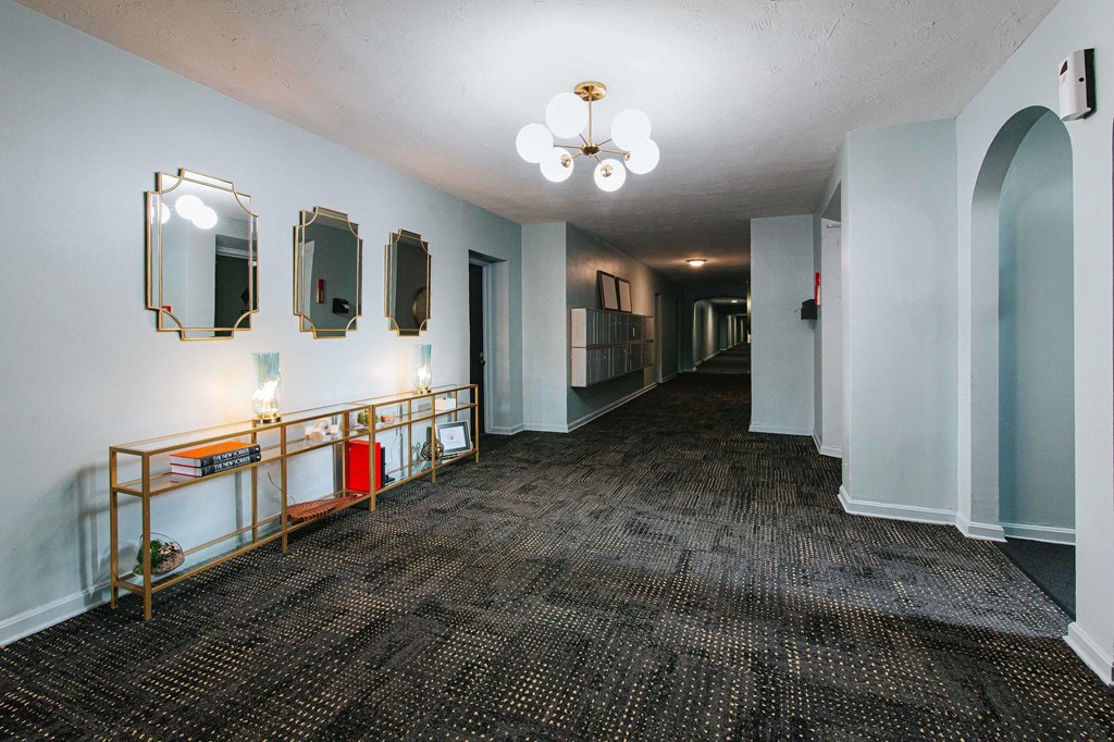 a room with a carpeted floor and a long hallway with mirrors on the wall