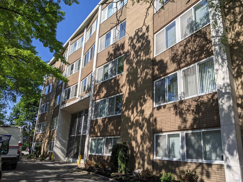 a large brick apartment building with tree shadows on it