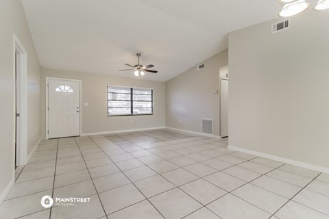 a spacious living room with tile flooring and a ceiling fan