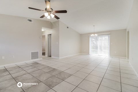 the spacious living room with tiled flooring and a ceiling fan