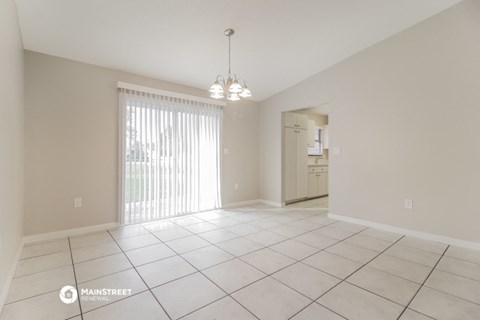 an empty living room with a sliding glass door to the kitchen