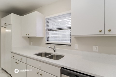 a kitchen with white cabinets and a sink and a window