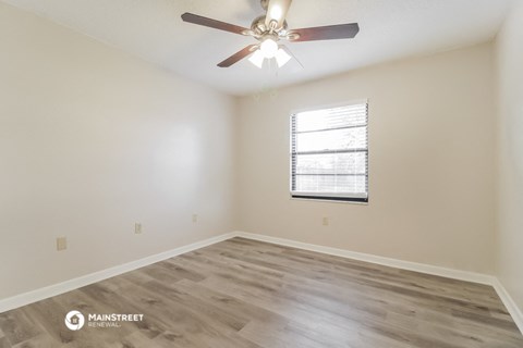 an empty room with a ceiling fan and a window