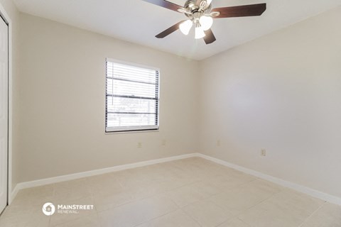 an empty room with a ceiling fan and a window